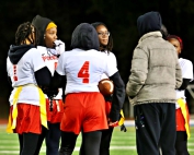 Stone Mountain made school history with its first flag football state playoff appearance on Thursday night. The Pirates came up short in a 20-0 loss to Therrell. Pictured (l-r) are Makayla Wilson (1), Serinity Brister (4) and Coach Sheena Harley (jacket) along with three unidentified Pirates during a timeout against Therrell. (Photo by Lester Wright)