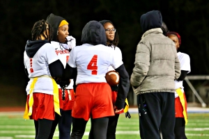 Stone Mountain made school history with its first flag football state playoff appearance on Thursday night. The Pirates came up short in a 20-0 loss to Therrell. Pictured (l-r) are Makayla Wilson (1), Serinity Brister (4) and Coach Sheena Harley (jacket) along with three unidentified Pirates during a timeout against Therrell. (Photo by Lester Wright)